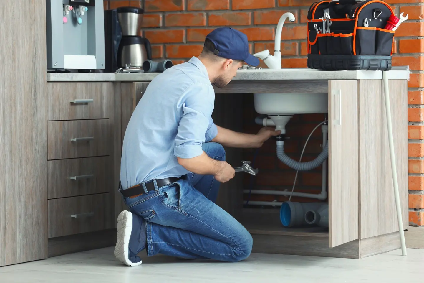 Intervention de plomberie sous un évier, outillage et raccords